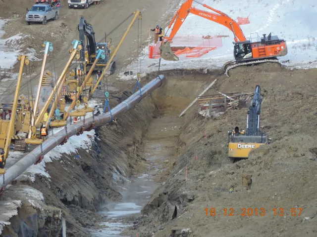 Midwest pipelayers and excavators supporting a pipeline section along a winter construction trench