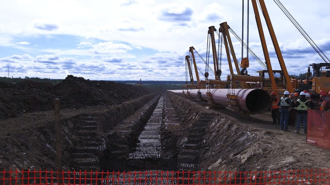 Midwest crews and pipelayers lowering a pipeline into a trench