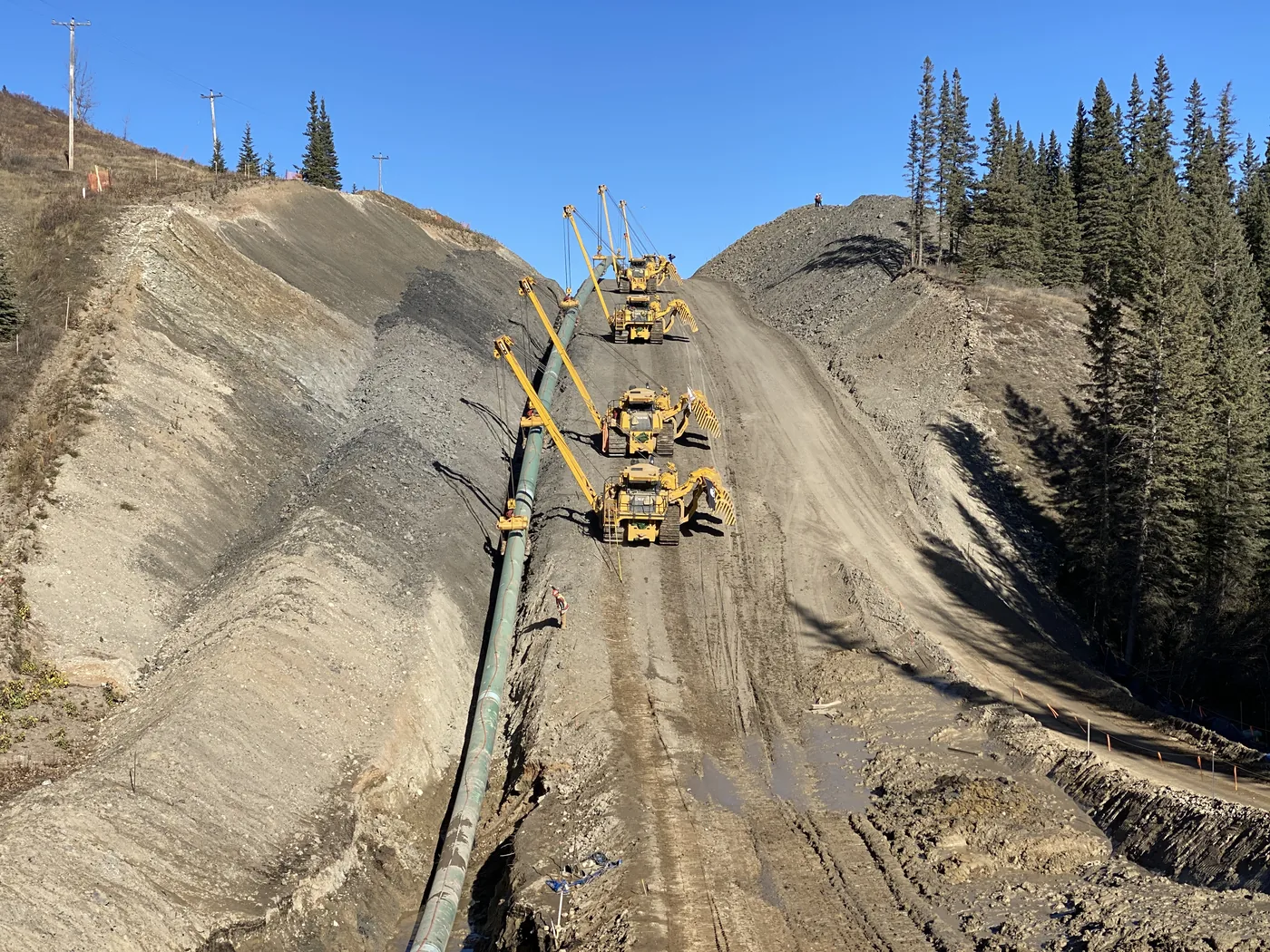 Pipelayers and pipe along a steep construction corridor
