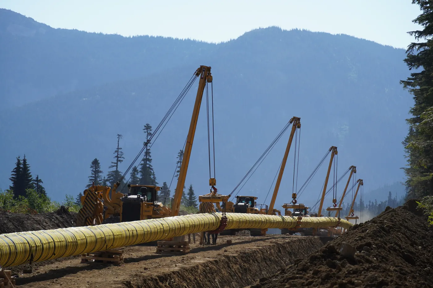 Midwest crews and pipelayers lowering a pipeline into a trench