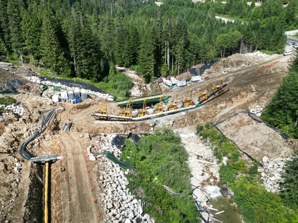 Pipelayers working along a prepared pipeline crossing beside a watercourse